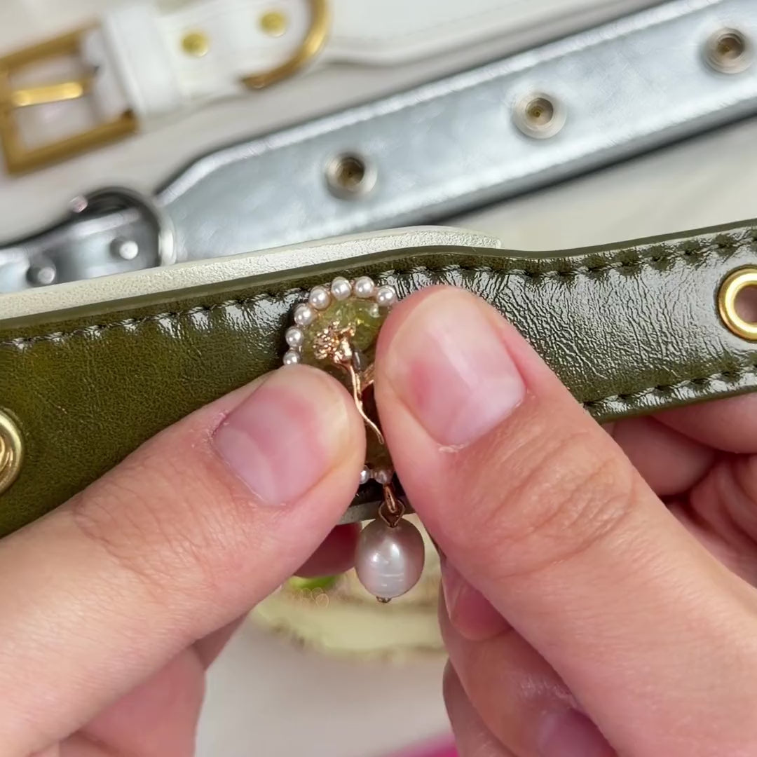 Hands snapping a green gemstone charm onto an olive collar