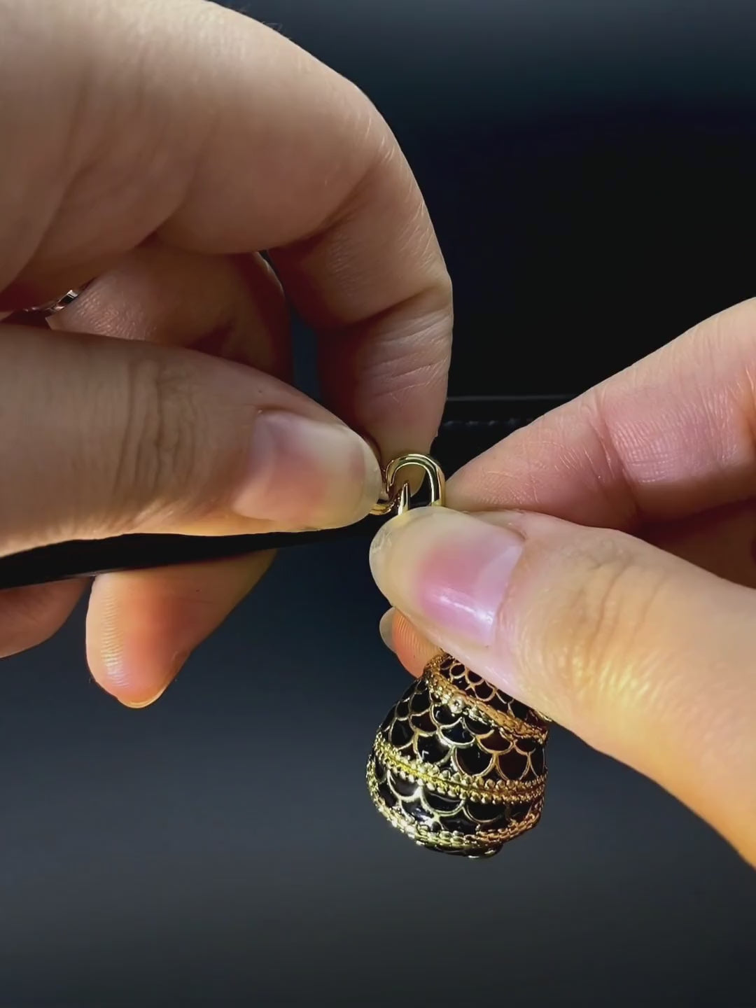 A gold filigree charm hanging from a black leather collar